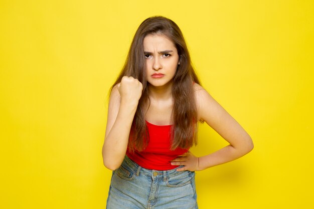 Een vooraanzicht jonge mooie dame in rood shirt en spijkerbroek met dreigende uitdrukking