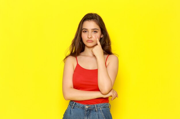 Een vooraanzicht jonge mooie dame in rood shirt en spijkerbroek met verveeld meningsuiting