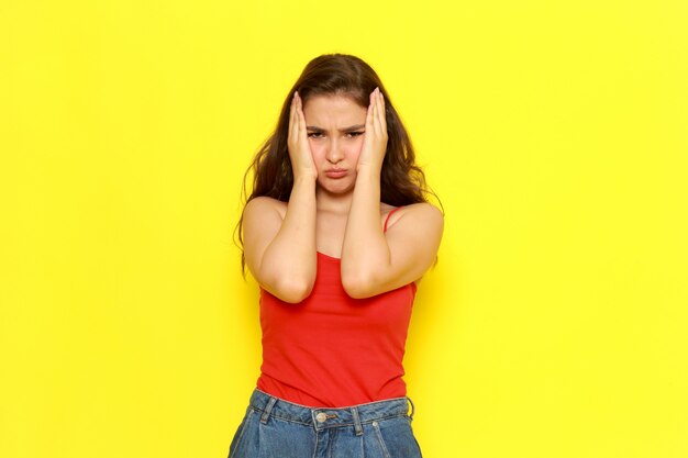 Een vooraanzicht jonge mooie dame in rood shirt en spijkerbroek poseren met gekke uitdrukking