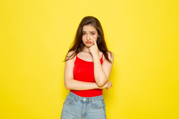 Een vooraanzicht jonge mooie dame in rood shirt en spijkerbroek poseren met gestresste uitdrukking