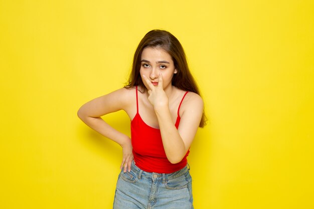 Een vooraanzicht jonge mooie dame in rood shirt en spijkerbroek poseren