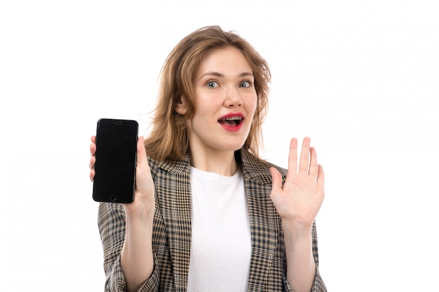 Een vooraanzicht jonge mooie dame in witte t-shirt zwarte jeans en laagholding die smartphone verraste uitdrukking op het wit tonen