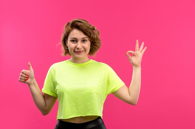 Een vooraanzicht jonge mooie dame in zuur gekleurde shirt zwarte broek lachend