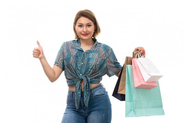 Een vooraanzicht jonge mooie vrouw die in gekleurde blousejeans het winkelen pakketten houden die het glimlachen stellen