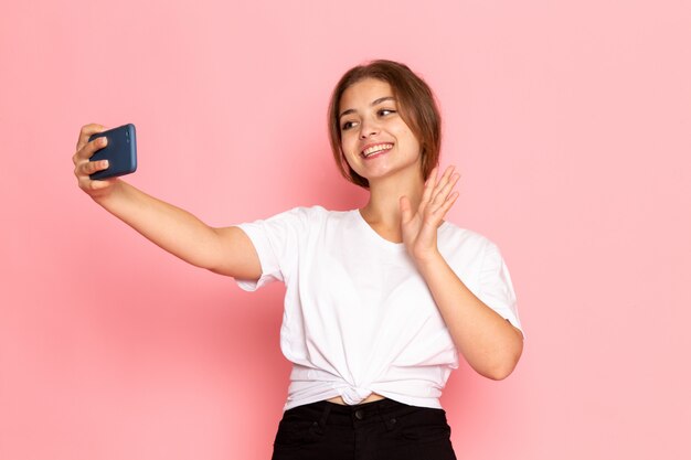 Een vooraanzicht jonge mooie vrouw in wit overhemd poseren met gelukkige uitdrukking en het nemen van een selfie