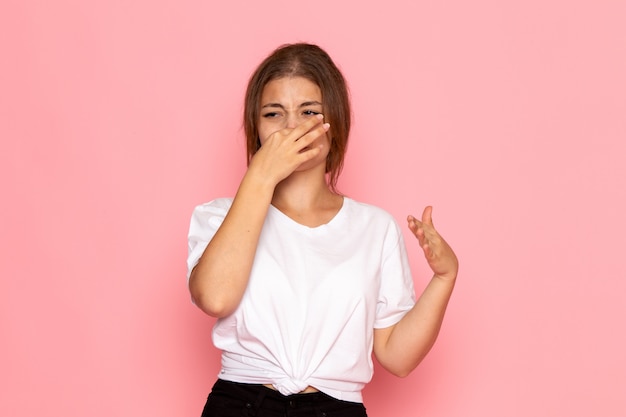 Een vooraanzicht jonge mooie vrouw in wit overhemd voor haar neus