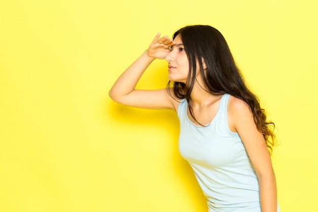 Een vooraanzicht jonge vrouw in blauw shirt poseren op zoek in de verte