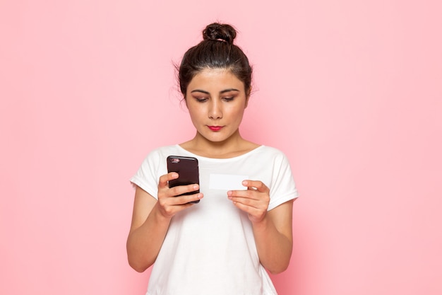 Een vooraanzicht jonge vrouw in wit t-shirt en spijkerbroek met behulp van een telefoon