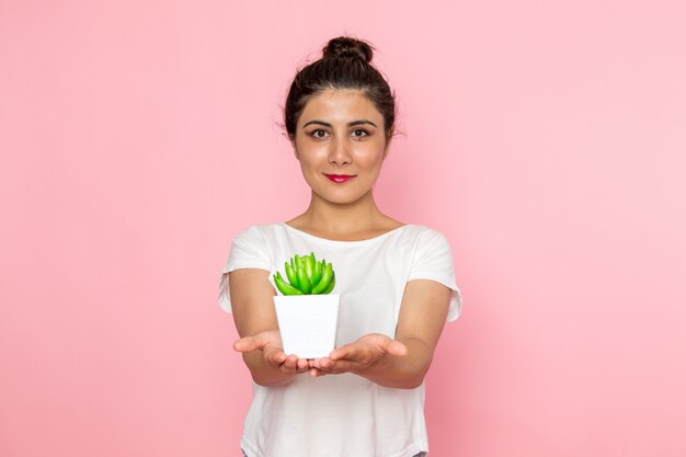 Een vooraanzicht jonge vrouw in wit t-shirt en spijkerbroek met kleine plant