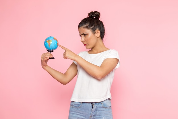 Een vooraanzicht jonge vrouw in wit t-shirt en spijkerbroek met kleine wereldbol