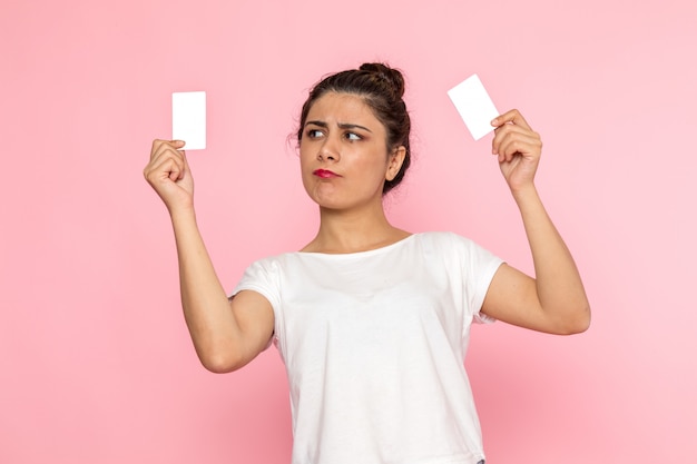 Een vooraanzicht jonge vrouw in wit t-shirt en spijkerbroek met witte kaarten