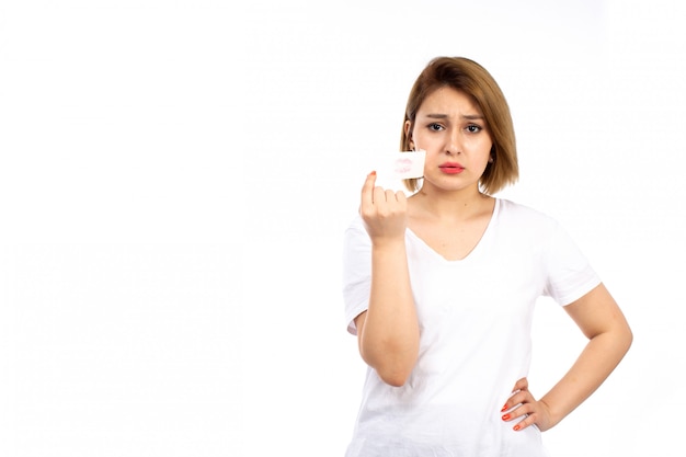 Een vooraanzicht jonge vrouw in wit t-shirt met wit verband rond haar mond opstijgen op de witte