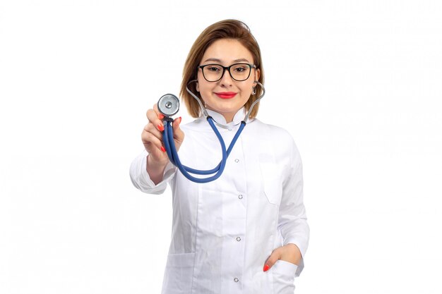 Een vooraanzicht jonge vrouwelijke arts in witte medische pak met een stethoscoop lachend op de witte