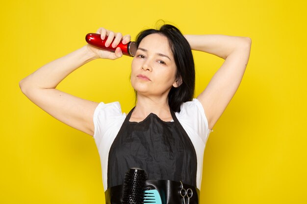 Een vooraanzicht jonge vrouwelijke kapper in witte t-shirt zwarte cape met behulp van mechanische haar machine golf haar