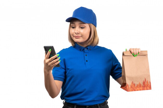 Een vooraanzicht jonge vrouwelijke koerier in blauw uniform bedrijfstelefoon en voedselbezorgingspakket