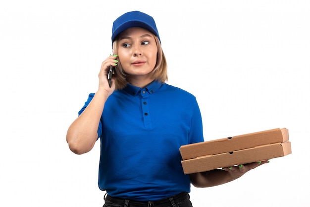 Een vooraanzicht jonge vrouwelijke koerier in blauwe uniforme telefoon- en voedselbezorgingspakketten