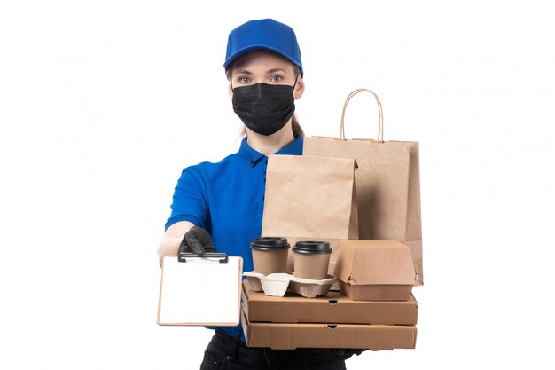 Een vooraanzicht jonge vrouwelijke koerier in blauwe uniforme zwarte handschoenen en zwart masker met voedselbezorgingspakketten