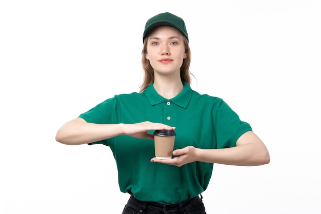 Een vooraanzicht jonge vrouwelijke koerier in een groen uniform lachend bedrijf koffiekopje