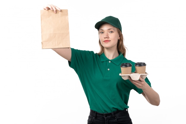 Een vooraanzicht jonge vrouwelijke koerier in groene uniforme lachende koffiekopjes en pakket te houden