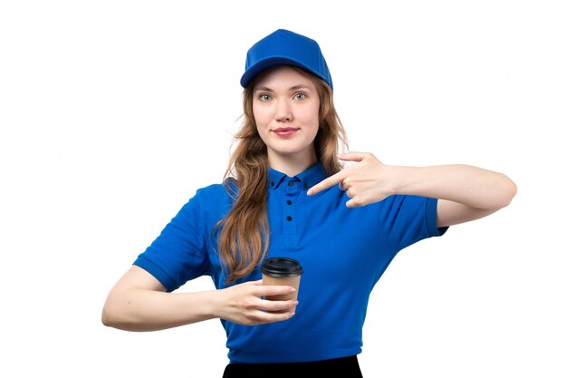 Een vooraanzicht jonge vrouwelijke koerier in het blauwe overhemd blauwe GLB het glimlachen kop van de holdingskoffie op wit
