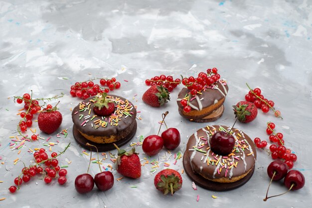 Een vooraanzicht kleine chocolade donuts met ontworpen en vers fruit op de hoogste chocolade van het cakefruit