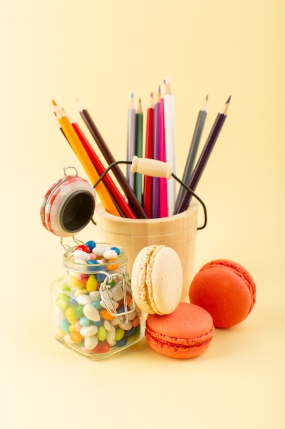 Een vooraanzicht kleurrijke snoepjes met Franse macarons en veelkleurige potloden