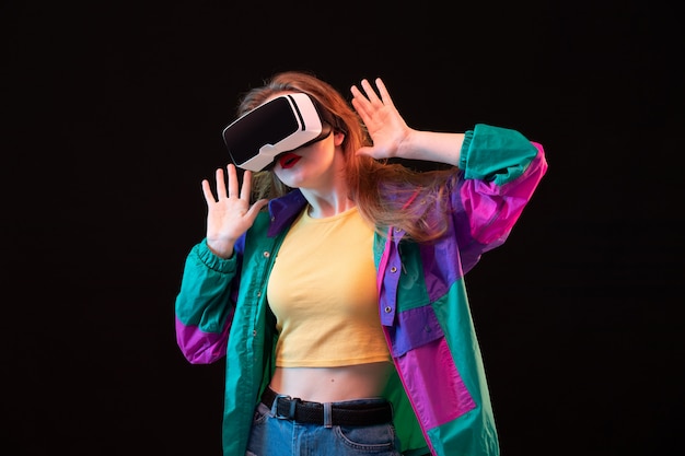 Een vooraanzicht moderne jonge dame in kleurrijke jas oranje t-shirt spelen en proberen vr op de zwarte achtergrond gaming interactief spel