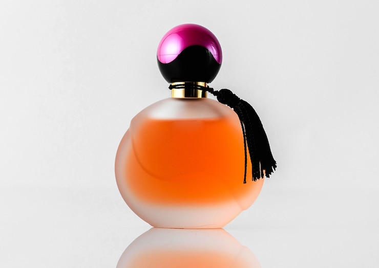 Gratis Foto een vooraanzicht oranje ontworpen parfum met zwarte en paarse dop geïsoleerd op de witte vloer