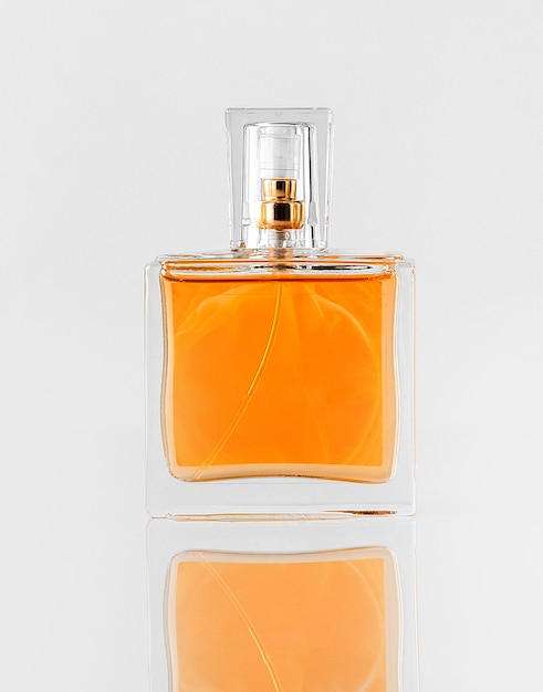 Een vooraanzicht oranje parfum in glas geïsoleerd op de witte vloer