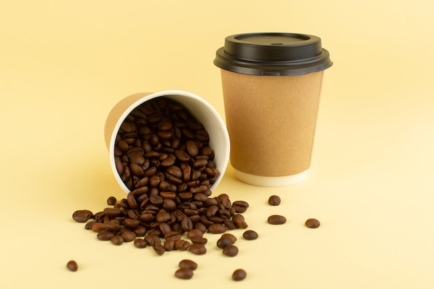 Een vooraanzicht plastic koffiekopjes met bruine koffiezaden op het gele oppervlak