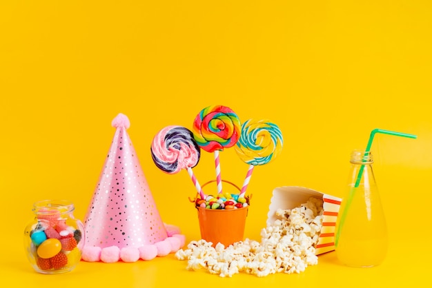 Een vooraanzicht popcorn en lollies met verse cocktail en kleurrijke snoepjes op geel