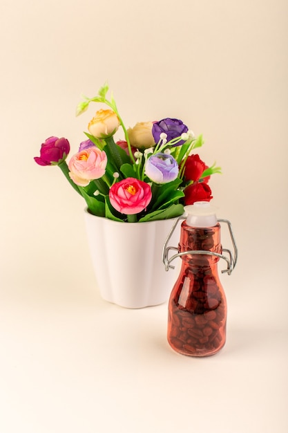 Gratis foto een vooraanzicht pot met koffie en bloemen op de roze tafelkoffie kleur bloemzaad