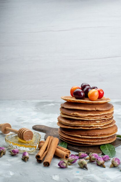 Een vooraanzicht rond gebakken pannenkoeken en heerlijk met kersen op het heldere fruit van de bureaucake