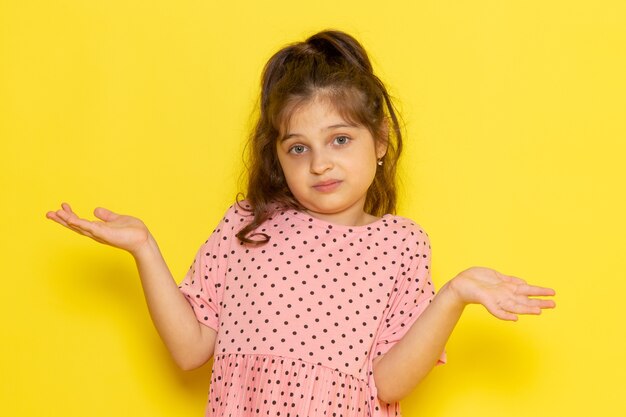 Een vooraanzicht schattig klein kind in roze jurk met een verwarde uitdrukking