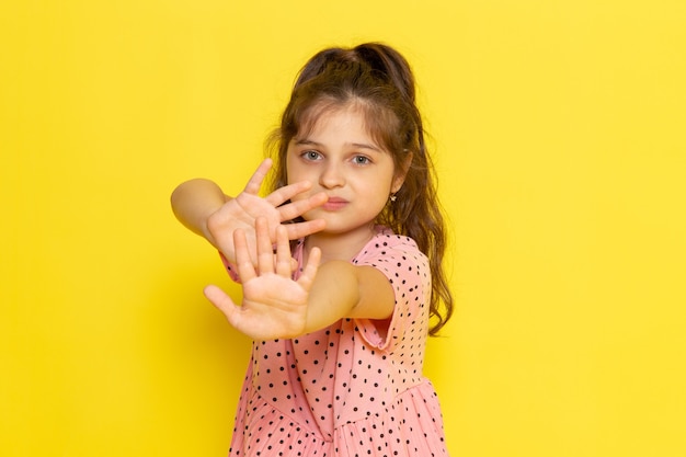 Een vooraanzicht schattig klein kind in roze jurk met een voorzichtige uitdrukking