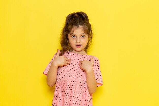 Een vooraanzicht schattig klein kind in roze jurk poseren