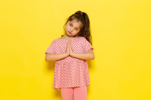 Een vooraanzicht schattig klein kind in roze jurk poseren