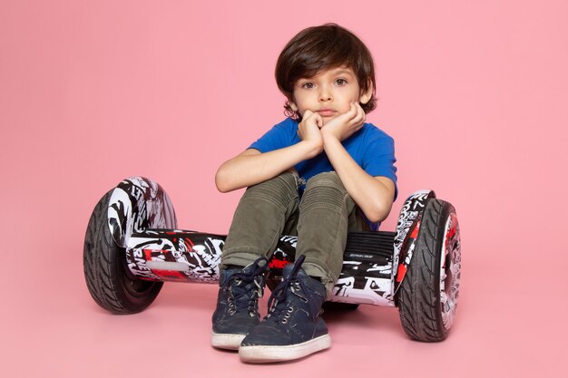 Een vooraanzicht schattige jongen in blauw t-shirt en kaki broek Segway rijden op de roze ruimte