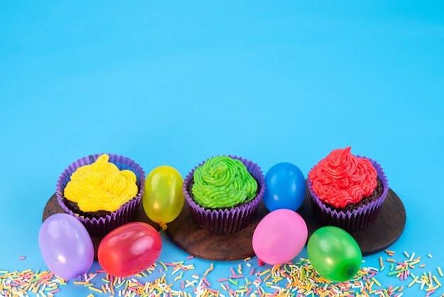 Een vooraanzicht van heerlijke brownies in paarse vormen op basis van chocolade, samen met snoepjes op blauw, snoepcake koekjeskleur