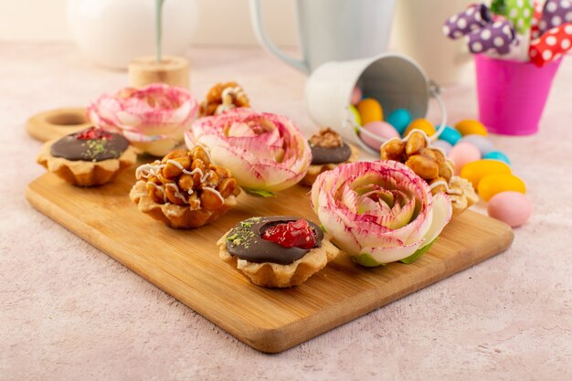 Een vooraanzicht van kleine chooclate cakes met bloemen en kleurrijke snoepjes