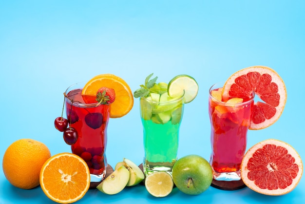 Gratis foto een vooraanzicht vers fruitcocktails met vers fruitplakken ijskoeling op blauw, drink de kleur van het sapcocktailfruit