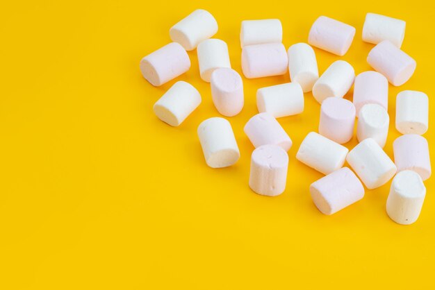 Een vooraanzicht witte marshmallows heerlijke zoetigheden op geel bureau, suiker zoete snoep kleur