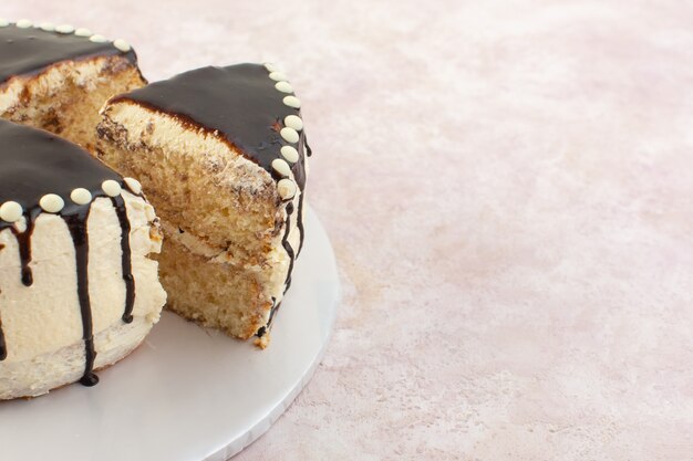 Een vooraanzichtchocolade plakjes binnen plaat op de roze zoete cake van de bureausuiker