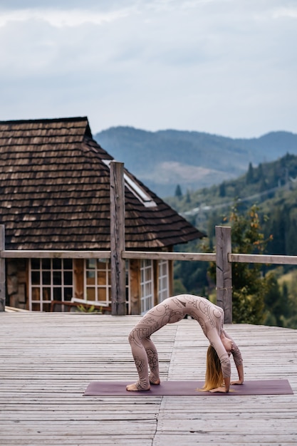 Gratis foto een vrouw beoefent yoga 's ochtends op een terras in de frisse lucht.