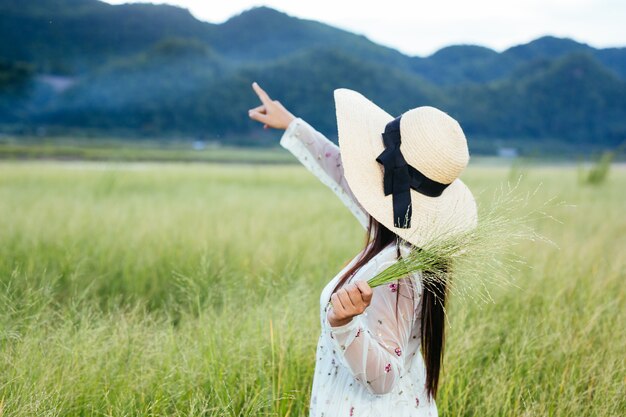 Een vrouw die een gras in haar handen houdt op een prachtig grasveld met een berg.