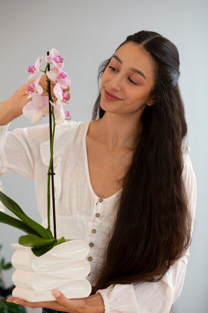 Gratis foto een vrouw die haar huis met orchideeën versiert