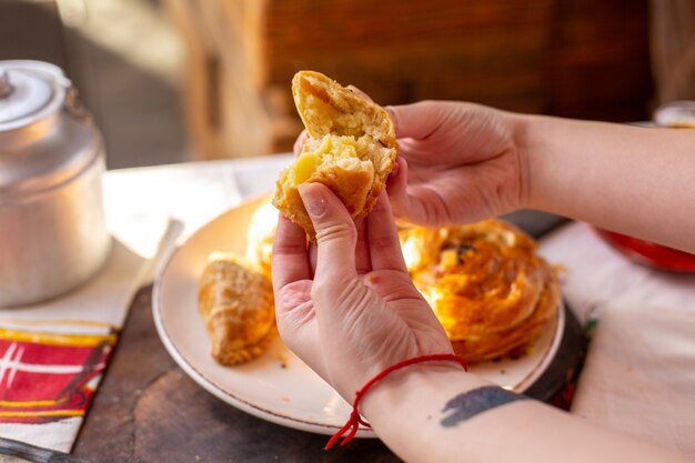 Een vrouw die van vooraanzichtgebakjes qogal scheuren samen met andere bakkerskoekjes theetijd smakelijke de deegceremonie van het gebakjegerecht op de lijst