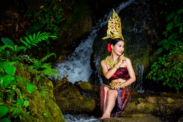 Een vrouw gekleed met een oude Thaise jurk bij de waterval.