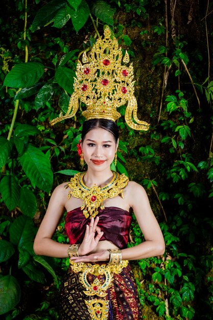 Een vrouw gekleed met een oude Thaise jurk bij de waterval.