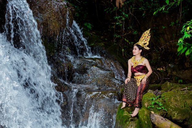 Een vrouw gekleed met een oude Thaise jurk bij de waterval.